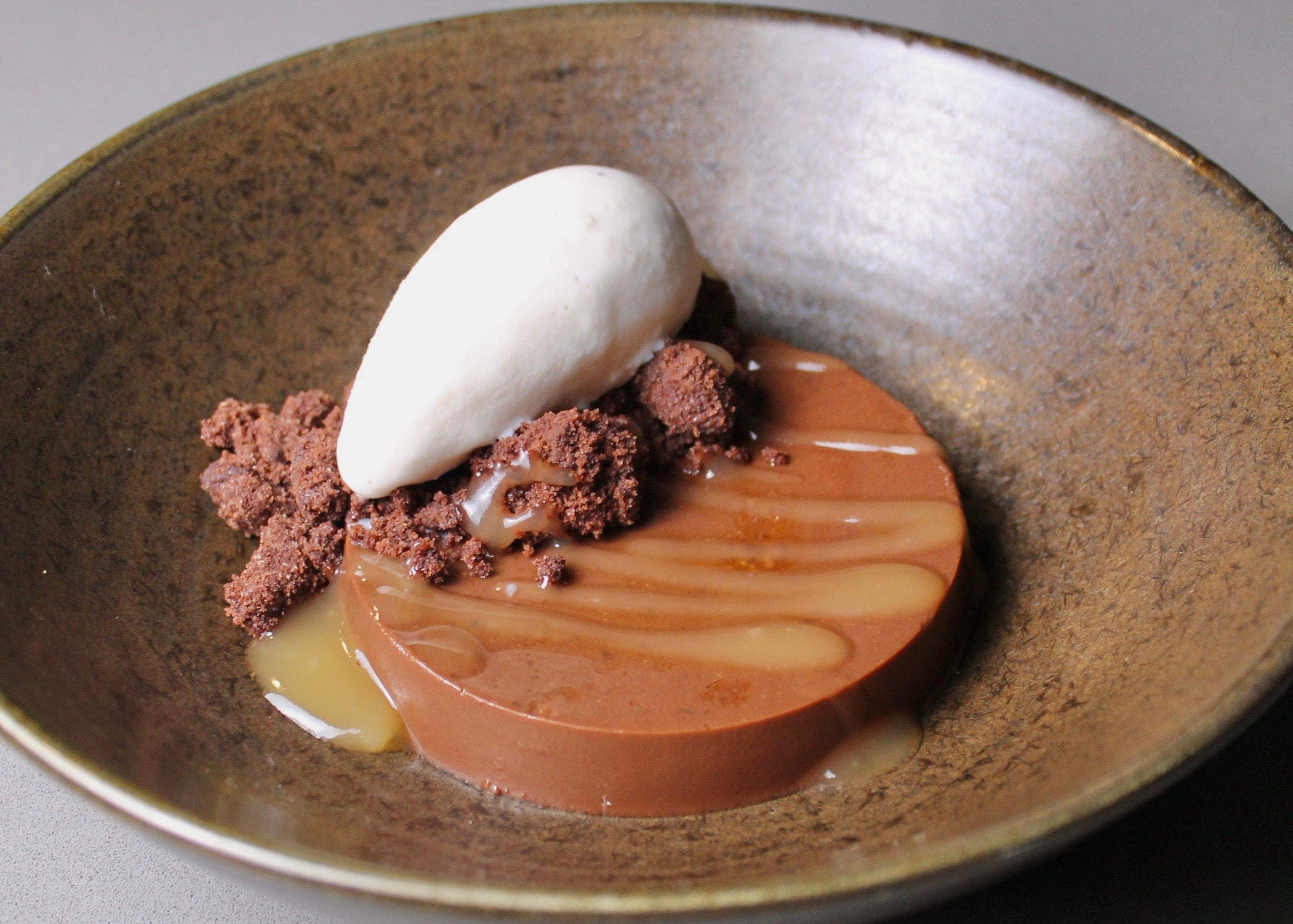 Dessert dish with a white cream topping on a wooden-textured plate