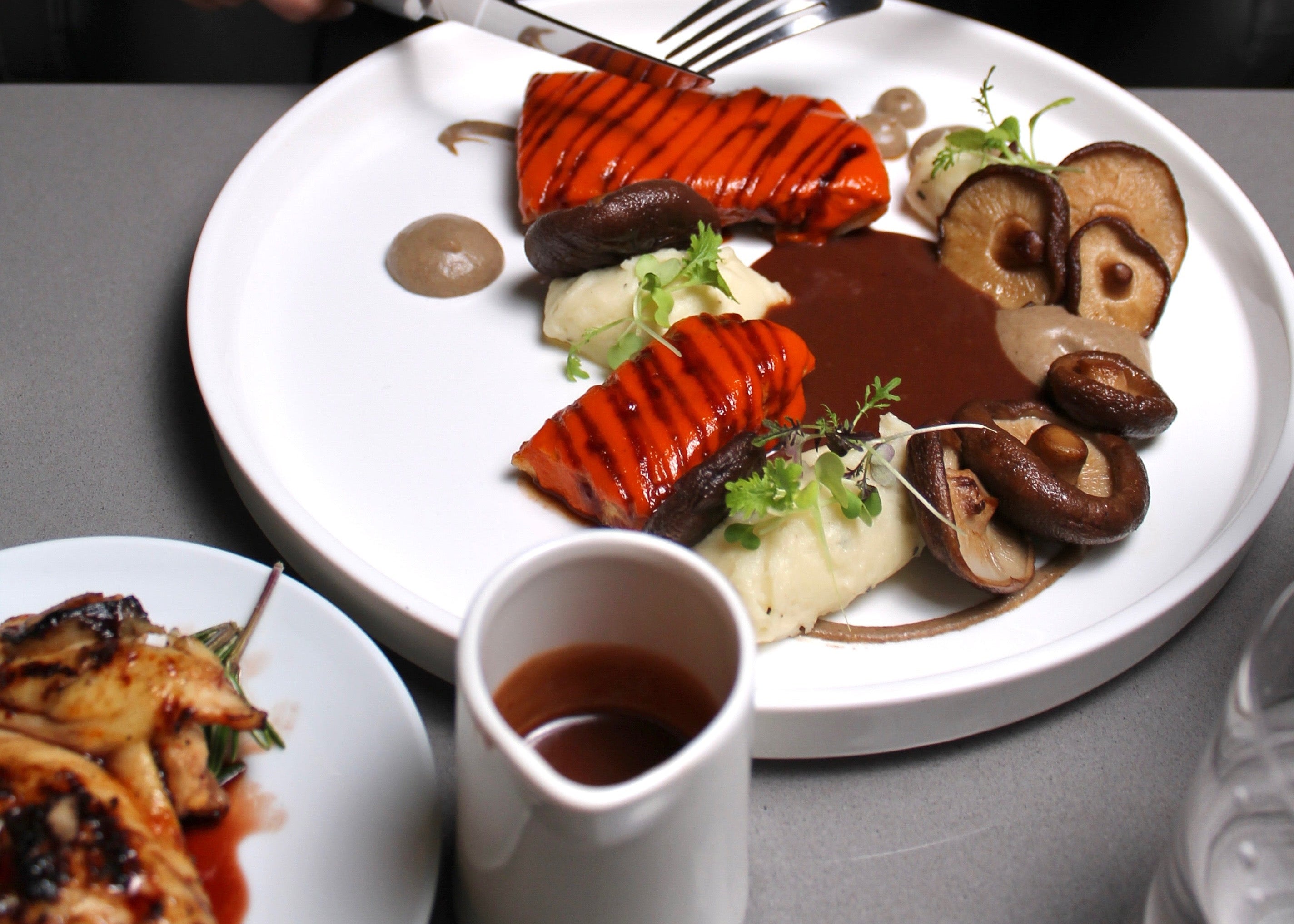 Person about to eat a plate of food with vegetables and sauce on a table.
